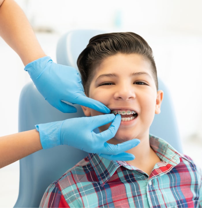 Boy getting braces adjusted in orthodontist office chair.